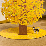 3d pop up greeting card of a japanese shiba inu standing under a big ginkgo tree displayed on a wooden desk