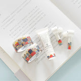 two rolls of gold foiled top quality washi tape displayed on an open book next to a pair of air pods