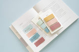 two sticky notes sets displayed on an open book with some sticky notes applied on the page