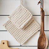 two handmade cotton insulation pad hanging on a kitchen rack with white tile background