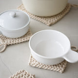 several cotton placemats displayed on a white surface with some small white pots on them