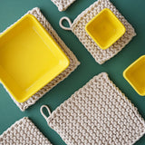 several cotton placemats displayed on a green surface with some yellow bowls on them