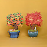 two 3d pop up greeting cards with one cachi tree on the left and one maple tree on the right