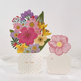 3d pop up greeting card of a bunch of flowers in a vase displayed on a white surface