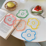 various transparent flower shaped acrylic coasters with colourful borders displayed on a desk