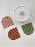 three colour silicon placemats displayed next to a white pot